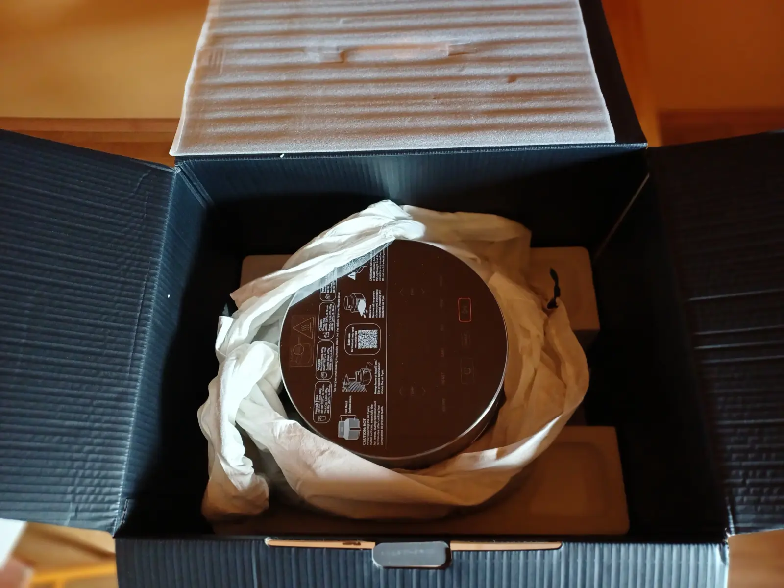 Blick in die geöffnete Verkaufsverpackung der COSORI ICONIC Single: Das Gerät ist sicher in weißem Papier und Styropor eingebettet.