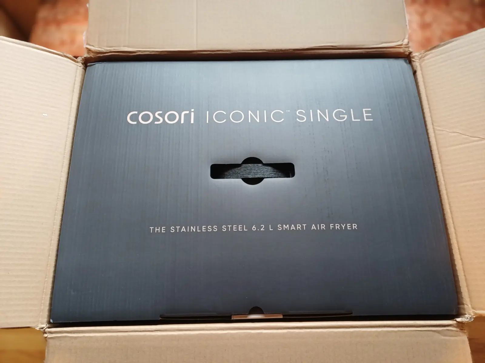 Auspacken der COSORI ICONIC Single: Die edle schwarze Produktverpackung mit silberner Aufschrift im GrünLotse Praxis-Check.
